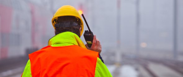 im Nebel spricht ein Arbeiter in sein Funkgerät